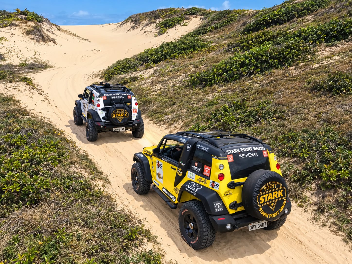 Dois jipes 4x4 em estrada de areia entre dunas